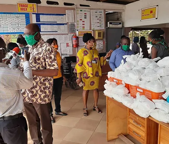 People in face masks standing beside tables of donated supplies at a hospital.